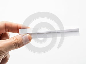 A hand holding a single white rectangular object against a white background
