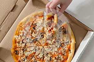 Hand holding slice pizza from the box.