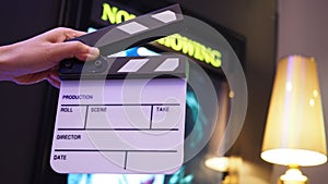 Hand is holding Small Clapperboard or movie slate  in front of cinemas . It use in video production, film industry.Black color