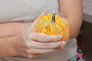 Hand Holding a Small Pumpkin. Cradling a vibrant orange and yellow patterned pumpkin