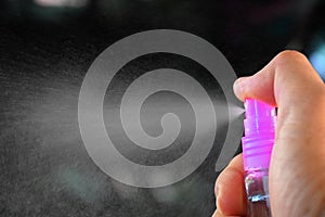 Hand holding a small spray bottle and spraying isolatedâ€‹  on blackâ€‹ background.â€‹concept of preventing the corona virus