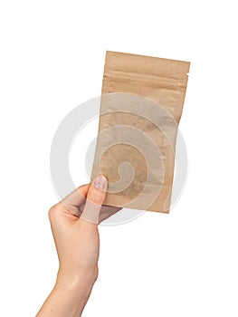 Hand holding small zip-lock kraft paper bag. Ziplock pouch, eco brown beige package