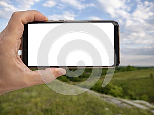 Hand holding smart phone with blurred backgroung. Blank screen for montage. Mockup image photo
