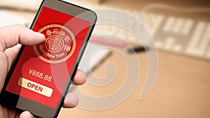 Hand holding smart phone with digital red packet for Chinese new year displayed on the screen