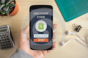 Hand holding smart phone with discount code concept on screen