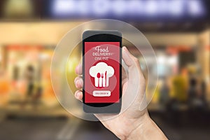 Hand holding smart phone with food delivery order screen.