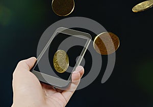 Hand holding smart phone and gold coin floating