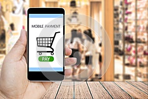 Hand holding smart phone with mobile payment and Shopping Cart.
