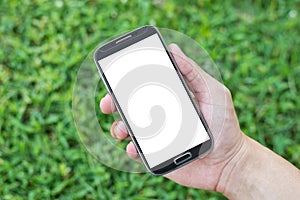 Hand holding smart phone (Mobile Phone) on grass background