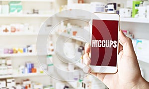 Hand holding smart phone in pharmacy drugstore. Text HICCUPS