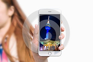 Hand holding smart phone with photo of Seoul tower.