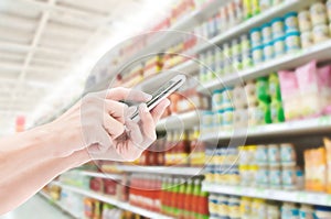 Hand holding smart phone on supermarketl backgrounds