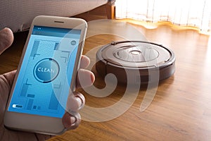 Hand holding smartphone with application control robot vacuum cleaner