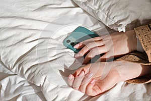 Hand holding smartphone on bed