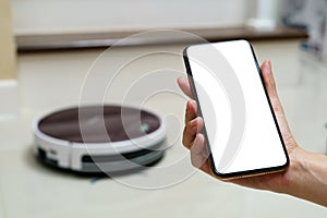 Hand holding smartphone with blanking screen for control robotic vacuum cleaner . Smart life technology concepts