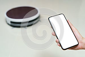 Hand holding smartphone with blanking screen for control robotic vacuum cleaner . Smart life technology concepts