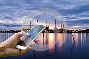 Hand holding smartphone on blurred Oil refinery industry plant a