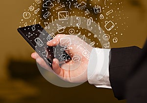 Hand holding smartphone with hand drawn media icons and symbols