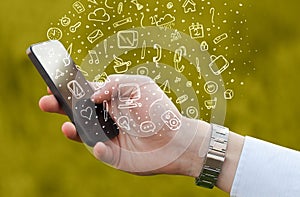 Hand holding smartphone with hand drawn media icons and symbols