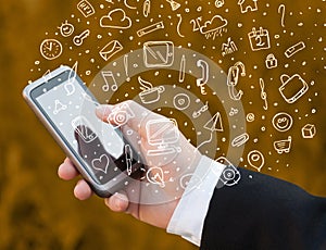Hand holding smartphone with hand drawn media icons and symbols