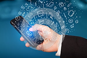 Hand holding smartphone with hand drawn media icons and symbols