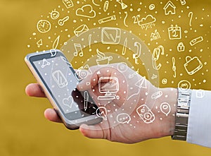 Hand holding smartphone with hand drawn media icons and symbols