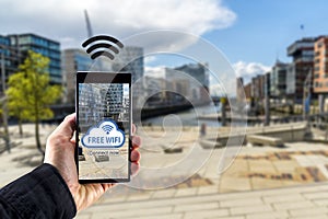 Hand holding smartphone mobile device with city in background