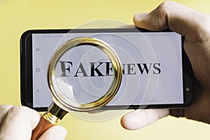 Hand holding smartphone with the phrase fake news written on the screen