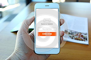 Hand holding smartphone with receive newsletter form screen on c