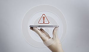 Hand holding smartphone with red triangle caution warning sign for notification error and maintenance concept