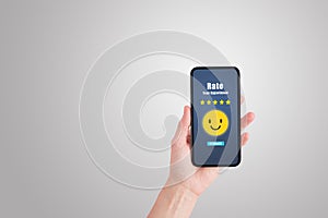 Hand holding smartphone that showing five yellow stars and smiley icons symbol for giving best service ranking.