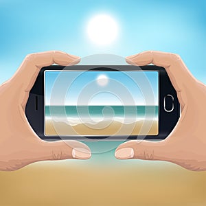 Hand holding smartphone and taking photo of the beach