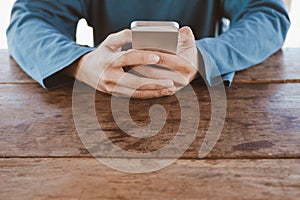 Hand holding smartphone on wooden table