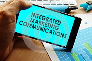 Hand holding smartphone with words integrated marketing communications.