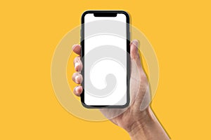 Hand holding smartphone on yellow background.