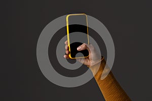 Hand Holding a Smartphone with a Yellow Case