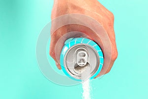 Hand holding soda can pouring a crazy amount of sugar in metaphor of sugar content of a refresh drink  on blue background