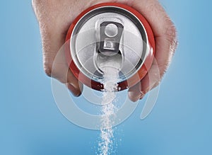 Hand holding soda can pouring a crazy amount of sugar in metaphor of sugar content of a refresh drink