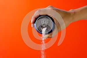 Hand holding a soda can pouring sugar