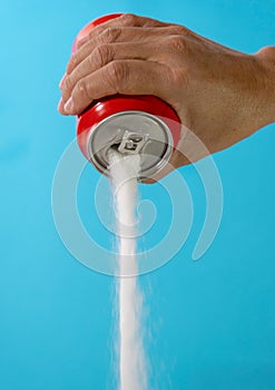 Hand holding a soda can pouring sugar