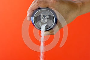 Hand holding a soda can pouring sugar