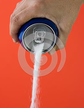 Hand holding a soda can pouring sugar