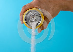 Hand holding a soda can pouring sugar