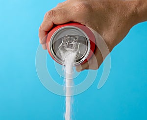 Hand holding a soda can pouring sugar