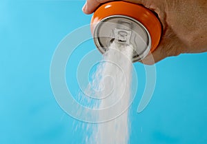 Hand holding a soda can pouring sugar