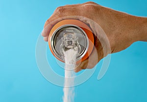 Hand holding a soda can pouring sugar