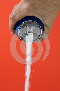 Hand holding a soda can pouring sugar