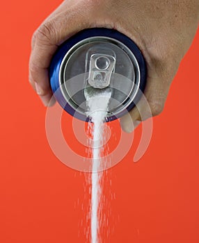 Hand holding a soda can pouring sugar