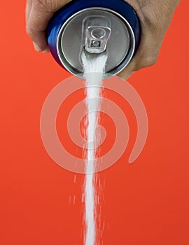 Hand holding a soda can pouring sugar