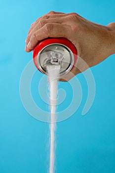 Hand holding a soda can pouring sugar